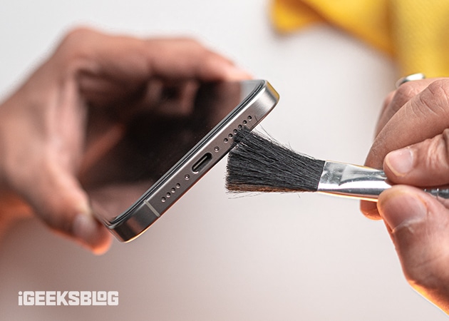 Cleaning the charging port of an iPhone with a soft bristled brush