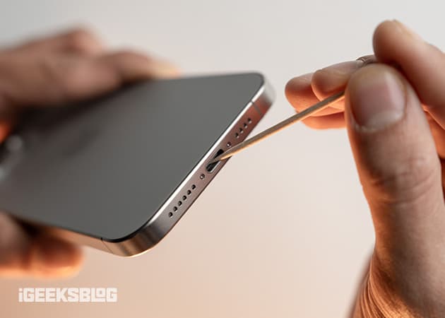 Using a toothpick to get rid of debris inside an iPhone's charging port.